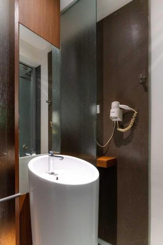 a bathroom with a sink and a phone on the wall at T+ Hotel Butterworth in Butterworth