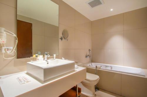 a bathroom with a sink and a toilet and a tub at Quest Hotel Tagaytay in Tagaytay