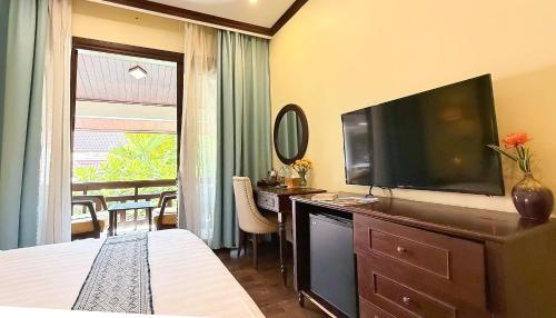 a bedroom with a large television on a dresser at La Palm Garden - Luang prabang in Luang Prabang