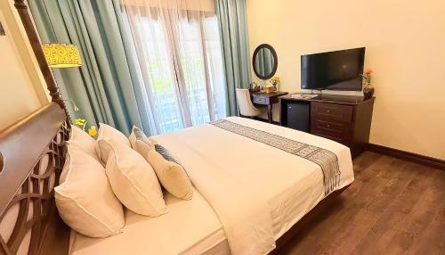 a hotel room with a bed and a television at La Palm Garden - Luang prabang in Luang Prabang