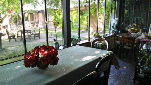 a table with a vase of red flowers on it at Alloggio Al San Girolamo in Longiano