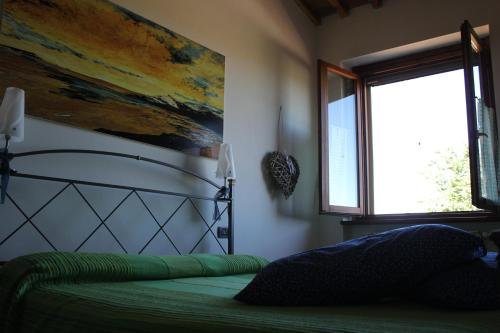 a bedroom with a bed with a painting on the wall at Agriturismo La Valle del Vento Urbino in Urbino