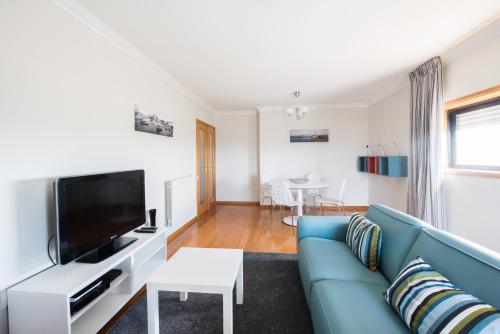 a living room with a blue couch and a tv at Porto RiverSea Quay Apartment in Matosinhos