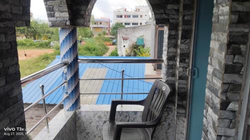 a chair sitting on a balcony looking out a window at Abhinandan Homestay in Shānti Niketan
