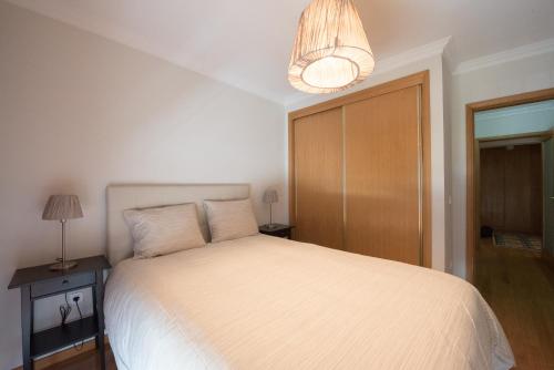 1 dormitorio con cama blanca y lámpara de araña en Porto RiverSea Quay Apartment, en Matosinhos
