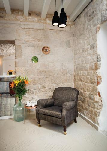 a chair sitting in a room with a stone wall at XII Century Heritage Hotel in Trogir