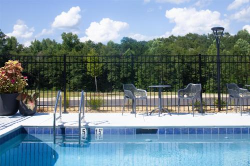 a pool with chairs and a table next to a fence at Hampton Inn Evergreen in Evergreen