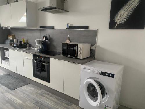 a kitchen with a washing machine and a microwave at Le Barbès in Montceau-les-Mines
