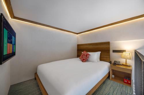 a bedroom with a large white bed and a tv at 上海浦东机场华美达安可酒店-免费提供24小时浦东机场班车十分钟到达候机楼出发层 in Shanghai
