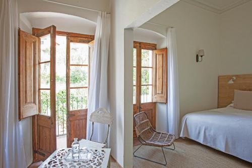 a bedroom with a bed and a chair and a window at Hotel Hanoi in Begur