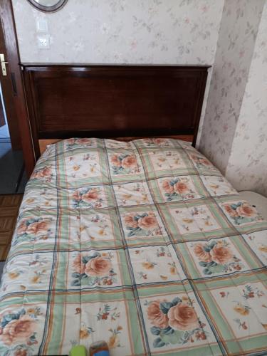 a bed with a floral comforter in a bedroom at Au charmes des cigognes in Sarralbe