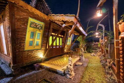 a wooden house with a porch at night at Villa Kaluna - 3 Bedroom Javanese Villa in Kaliurang in Bedoyo