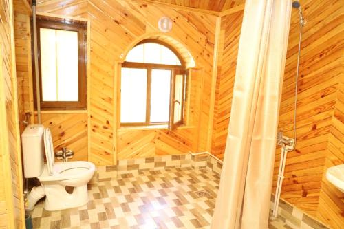 a wooden bathroom with a toilet and a shower at Farid HOSTEL in Ganja