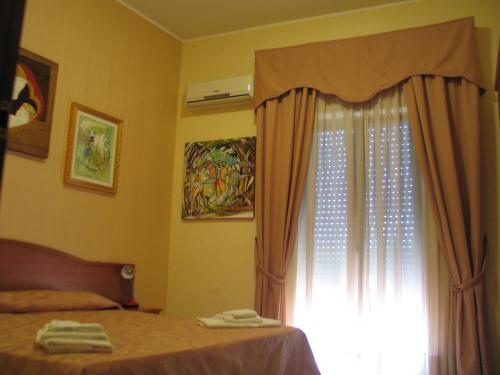 a bedroom with a bed and a window with towels at Hotel Bed & Breakfast Minu' in Paravati