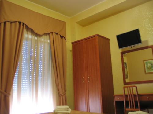 a bedroom with a window and a dresser and a television at Hotel Bed & Breakfast Minu' in Paravati