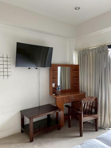 a bedroom with a desk and a television on the wall at Bake Room Hostel in Chiang Mai