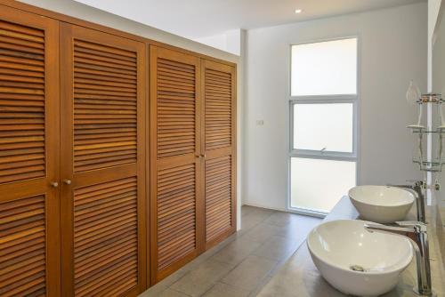 a bathroom with wooden cabinets and a sink and a toilet at 3br Villa Private Pool 10min To Beach in Mae Nam