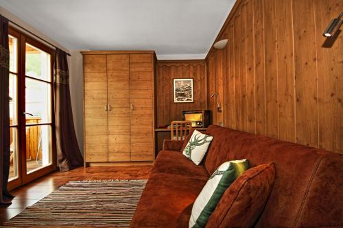 a living room with a brown couch and wooden walls at Appartamento Zepp in Bormio