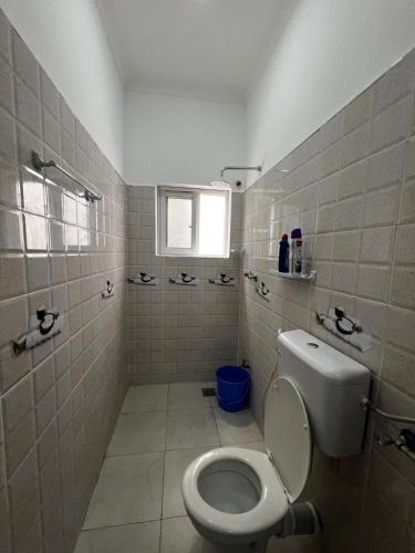 a white bathroom with a toilet and a window at Malindi Tee Homes in Malindi