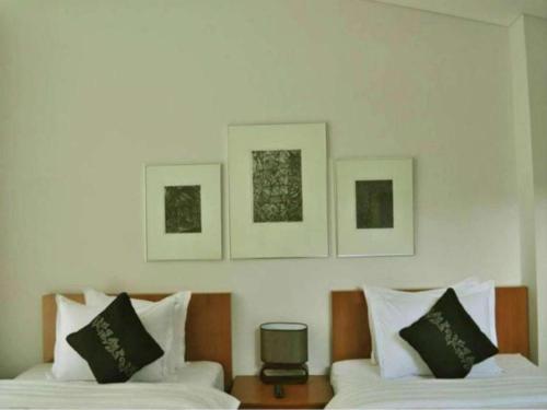 two beds in a room with three pictures on the wall at VillaTel Salse in Bandung