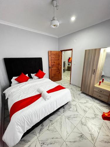 a bedroom with a large white bed with red pillows at Malindi Tee Homes in Malindi