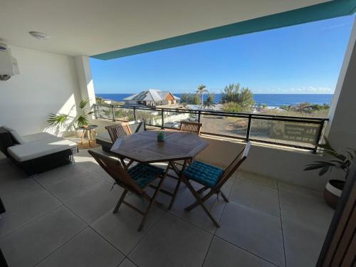 a table and chairs in a room with a view of the ocean at Aurora Appart in Trois Bassins