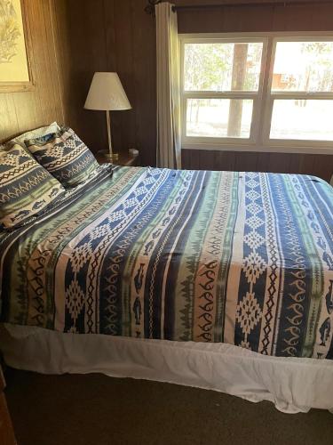 a bedroom with a bed with a quilt and a window at Grandma's Home in the Woods. Yellowstone in Island Park