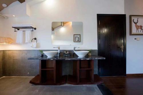 a bathroom with two sinks and a mirror at Lugu Lake Yunshang Holiday Hotel in Zuosuo
