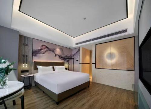 a bedroom with a large white bed and a table at 上海野生动物园荷逸唐酒店-惠南地铁站店 in Nanhui