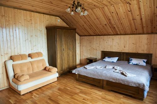 a bedroom with a bed and a couch in a room at Panskyi Kut in Bukovel