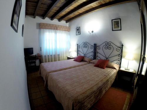 a bedroom with a large bed with red pillows at Casa Rural El Regajo Valle del Jerte in El Torno