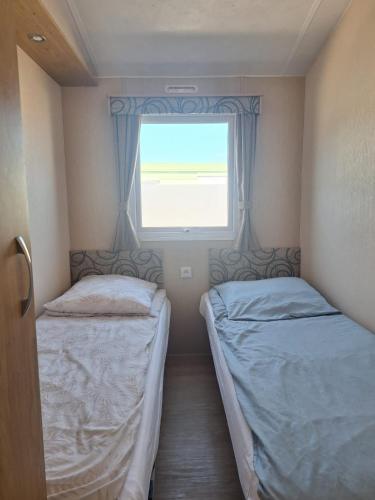 two beds in a small room with a window at Sunset Spot à Bredene in Bredene