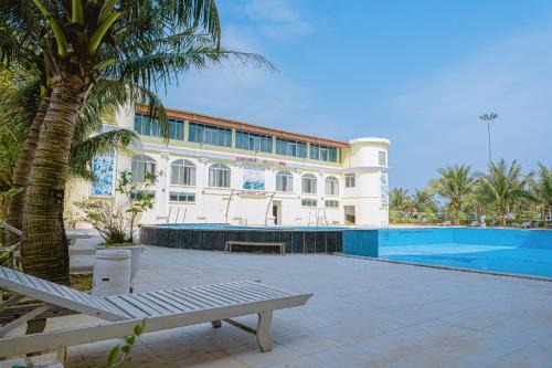 ein großes Gebäude mit einem Swimmingpool neben einer Palme in der Unterkunft Paracel Resort Hai Tien in Mỹ Ðuc