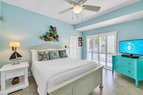 a blue bedroom with a bed and a television at Waterfront Covered alfresco lounge Heated Pool Anchor Key in Islamorada