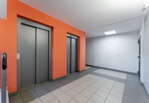 an empty hallway with orange and white walls and doors at Osiedle Piastów Charming Apartment by BookingHost in Kraków