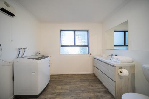 a white bathroom with a sink and a mirror at Four Peaks on Matai - Te Anau Holiday Home in Te Anau