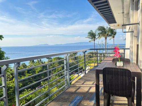 a balcony with a table and chairs overlooking the ocean at AV Suites in Puerto Galera