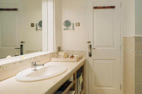 a white bathroom with a sink and a mirror at Tauch Terminal Resort Tulamben & Spa in Tulamben