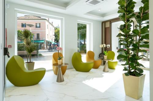 a lobby with green and yellow chairs and potted plants at Melia Venezia Lido in Venice-Lido