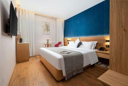 a hotel room with a large bed and a tv at New Beacon Sunyee SPA Hotel in Wuhan