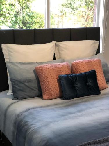 un grupo de almohadas sentado encima de una cama en Gisborne large family home with wifi, en Gisborne