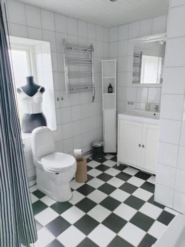 a bathroom with a toilet and a black and white checkered floor at Storstugan nära havet in Ystad