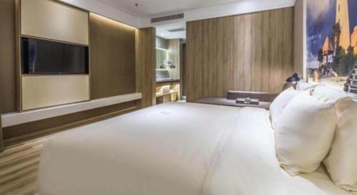 a bedroom with a large white bed with a television at Atour Hotel Weihai Shidao in Dongshan