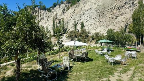 a group of chairs and umbrellas in the grass at Escape Retreat Hunza in Karimabad Hunza