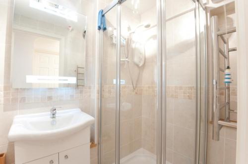 a bathroom with a glass shower and a sink at Seaspray in Saint Mawes