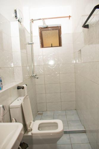 a white bathroom with a toilet and a sink at The African touch in Galu
