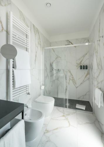 a white bathroom with a toilet and a sink at Melia Venezia Lido in Venice-Lido