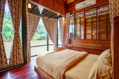 a bedroom with a bed and a large window at The For Rest Resort in Sai Yok