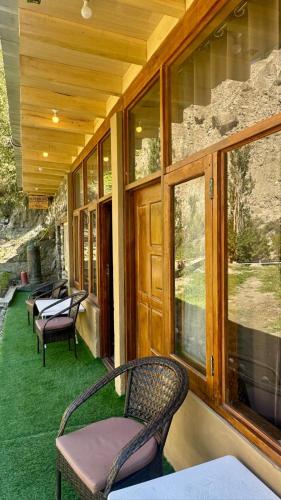 a porch with chairs and windows on a house at Escape Retreat Hunza in Karimabad Hunza