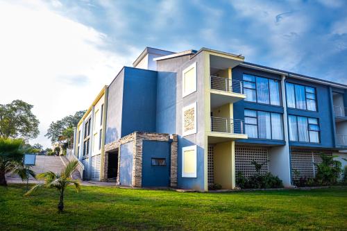 a blue and white building with a grass yard at Happy Valley Hotel and Casino in Ezulwini
